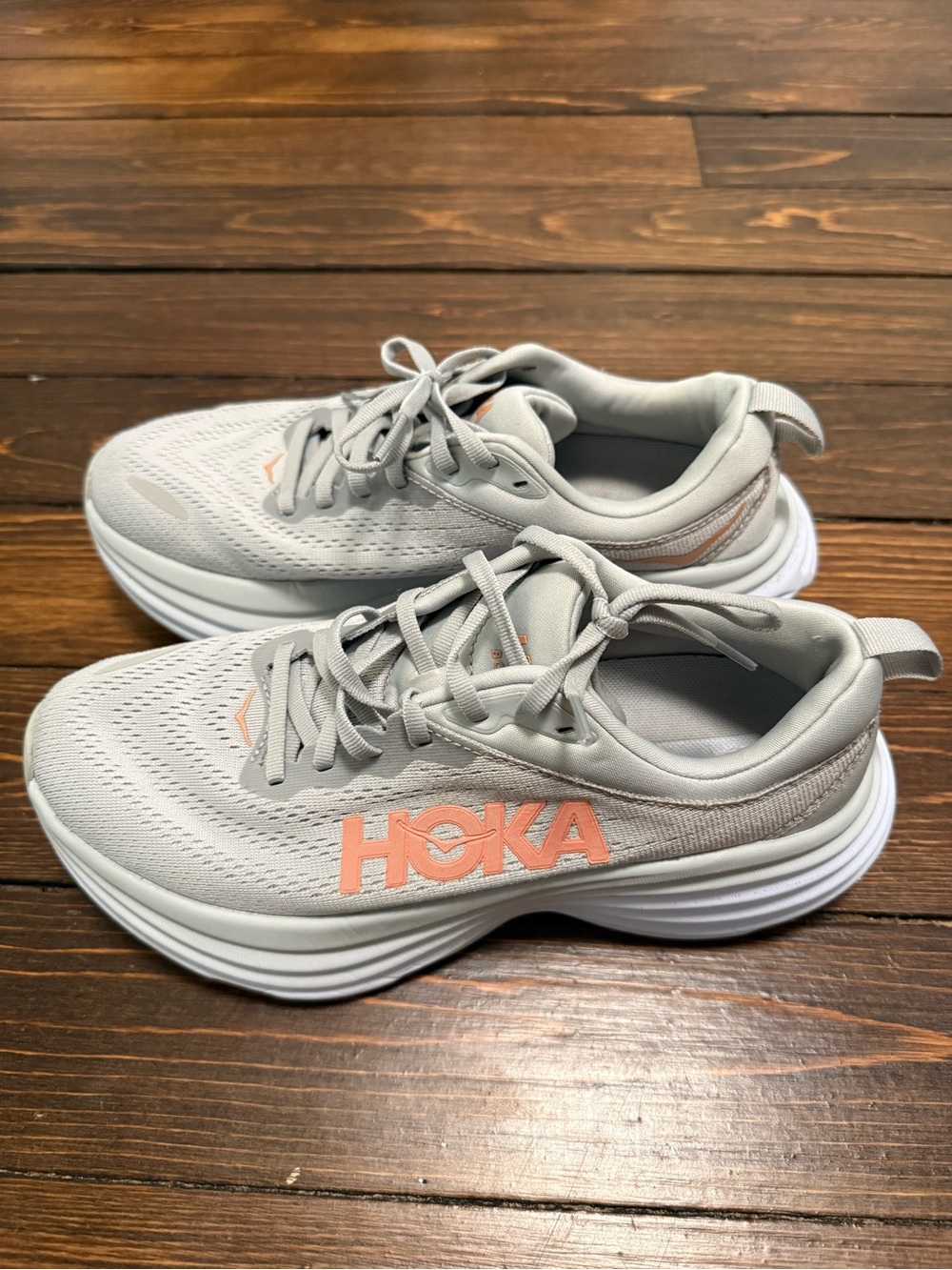 Hoka light gray running shoes with coral logo